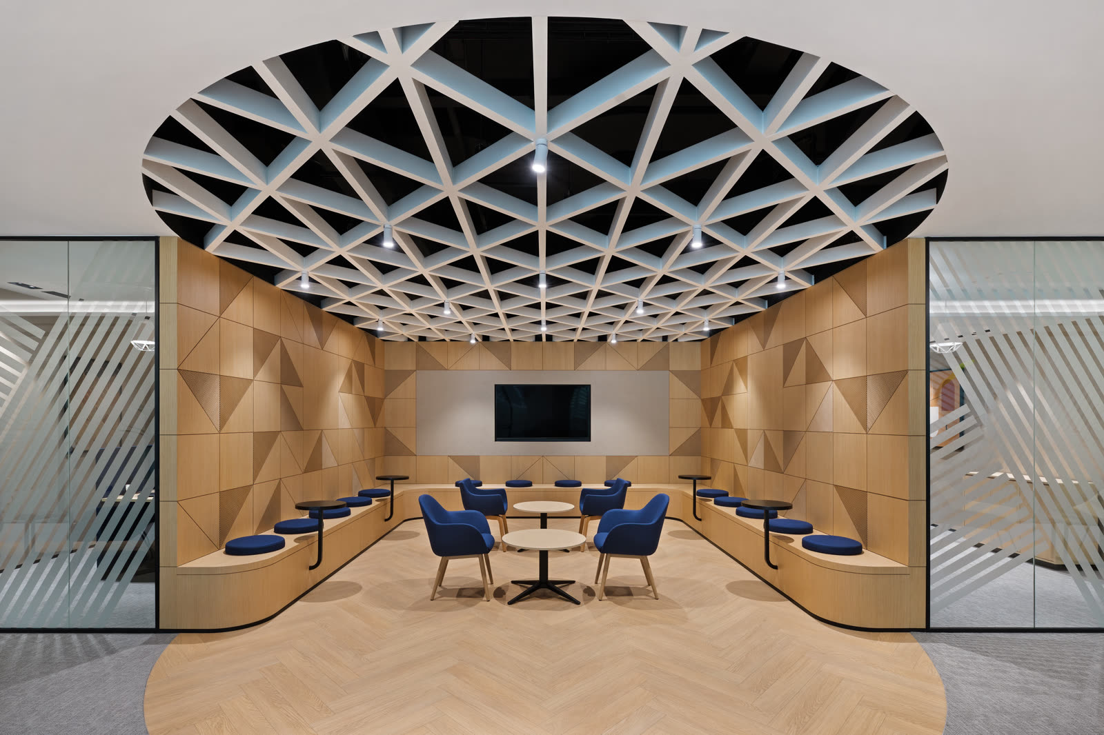 Meeting lounge with a circular lattice ceiling, timber wall and blue chairs