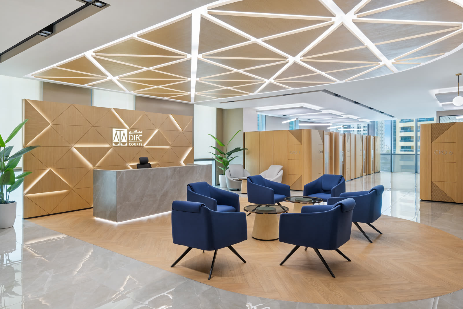 Reception with a faceted timber wall, geometric ceiling lights and blue armchairs