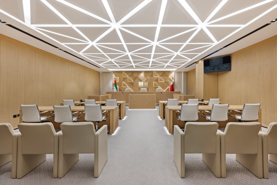 Courtroom with pale upholstered chairs facing the bench under a geometric ceiling light