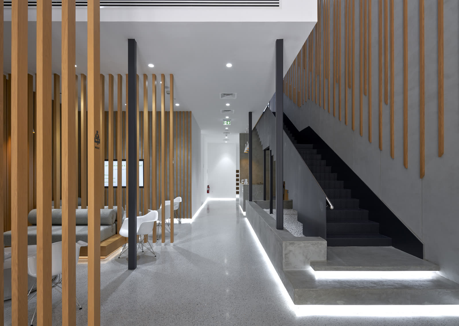 Corridor lined with vertical timber slats beside a black staircase