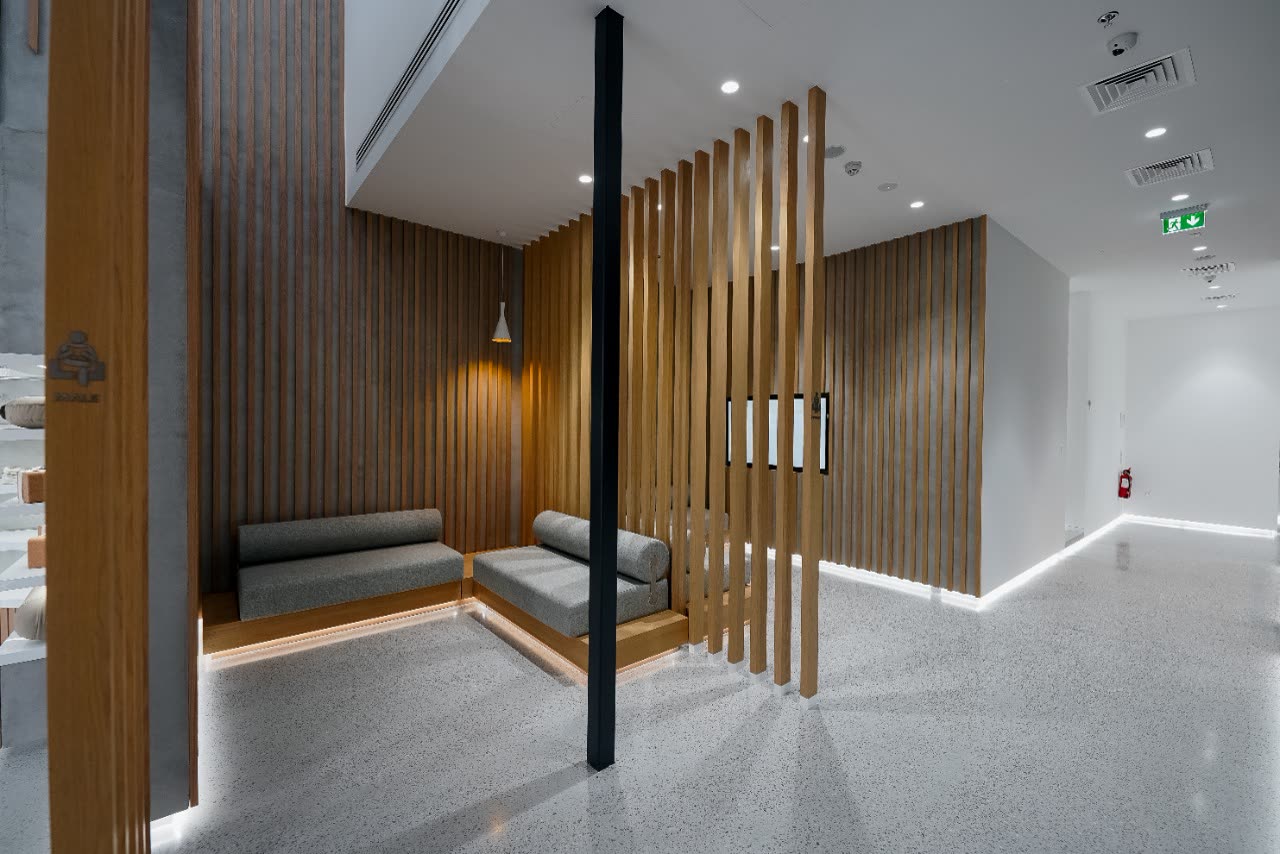Timber slat screens around a grey seating nook beside a black column