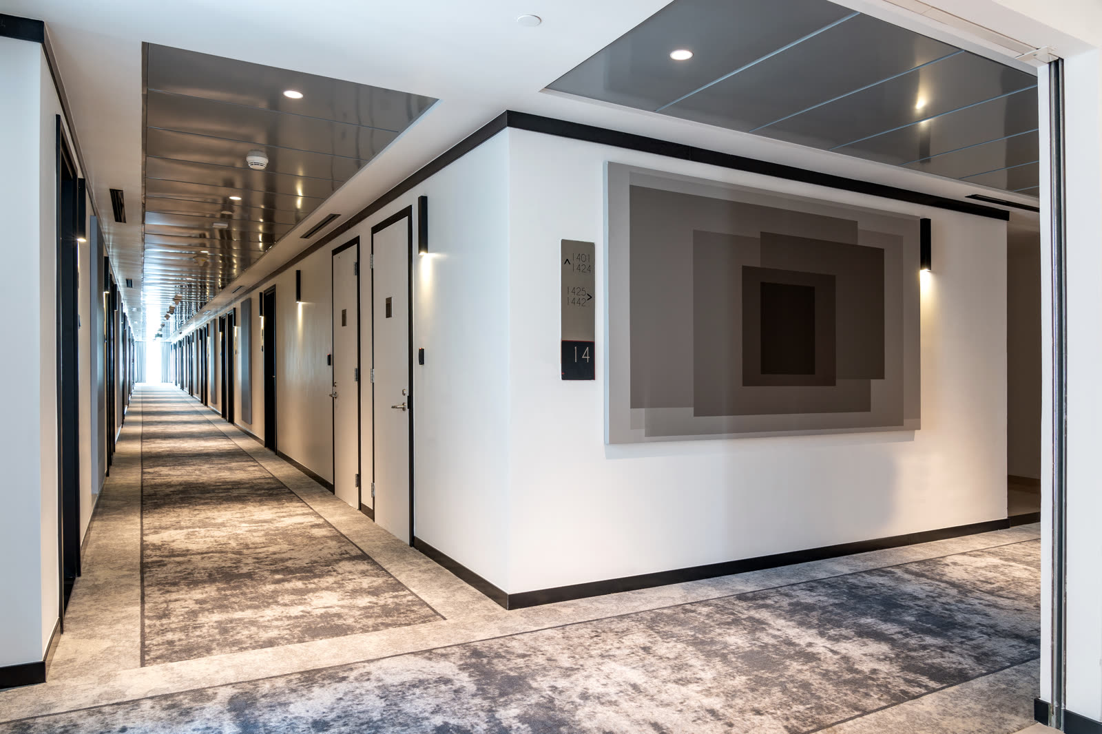 Corridor with a geometric grey artwork and a patterned carpet