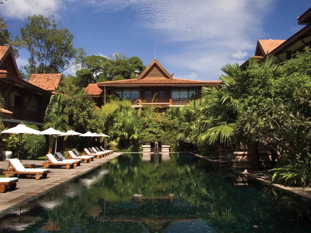 Pool with loungers, parasols and traditional timber pavilions among palms