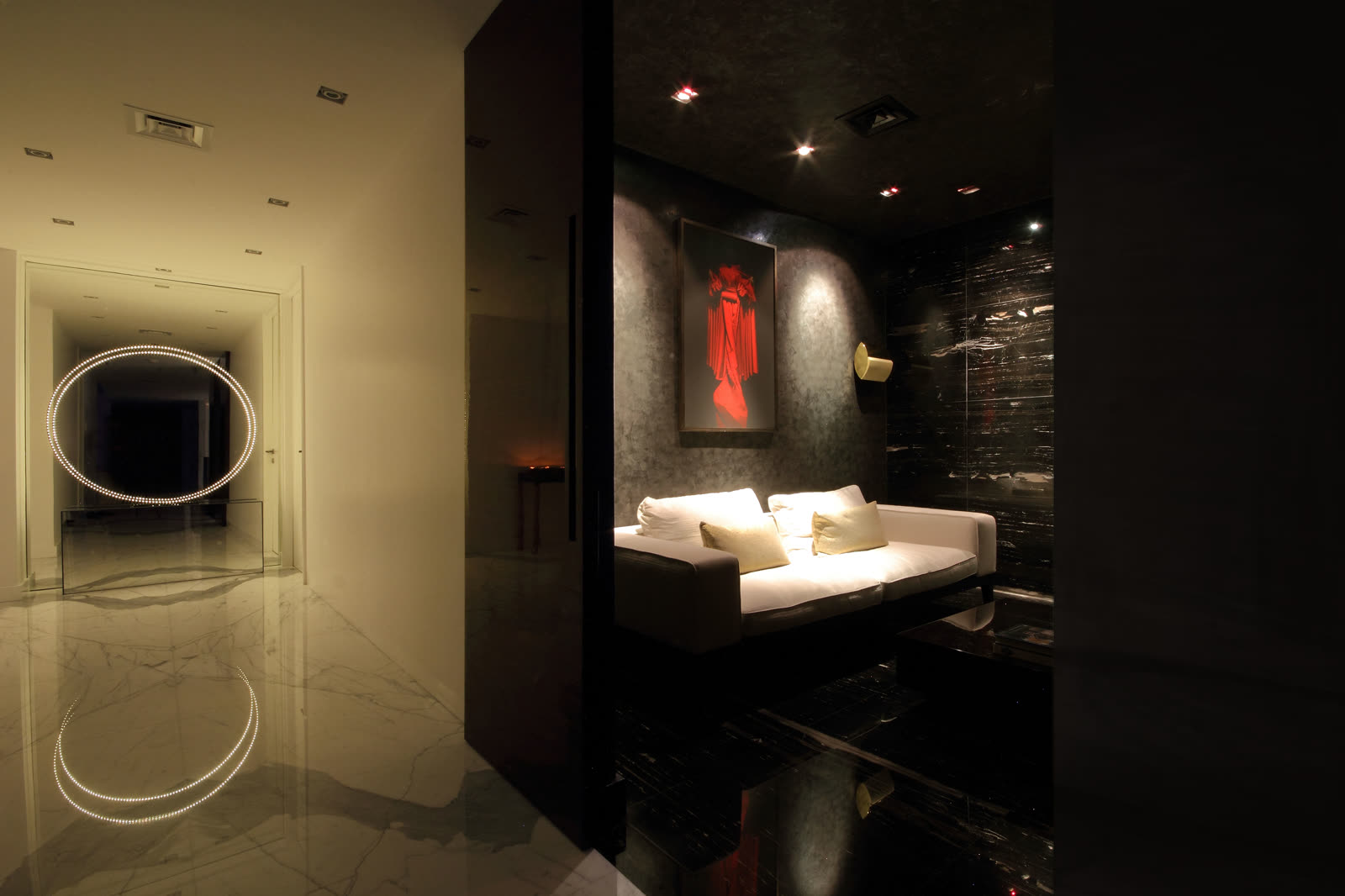 Lit circular feature and a dark marble room with a sofa and red artwork