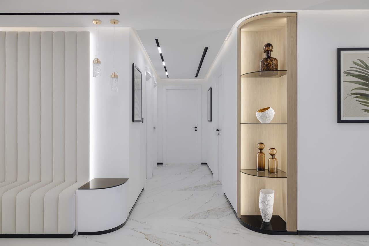 Marble-floored hallway with curved white joinery and lit display shelves
