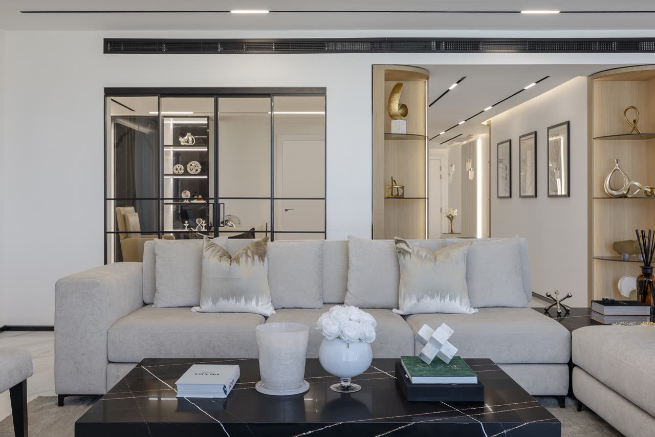 Living room with a cream sofa, black marble coffee table and glass-fronted display niches