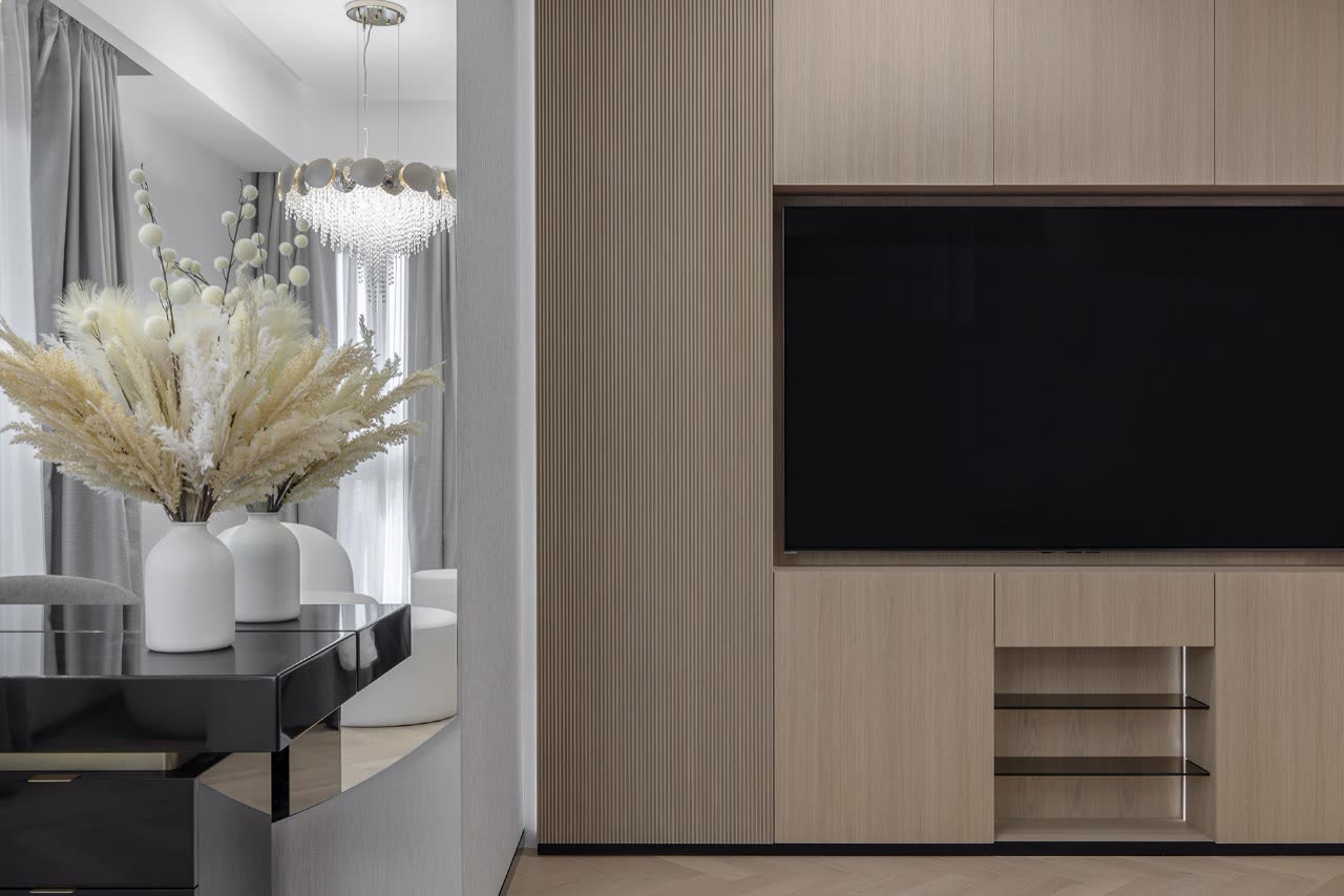Entrance detail with a console, dried pampas flowers and a chandelier beside a timber media wall