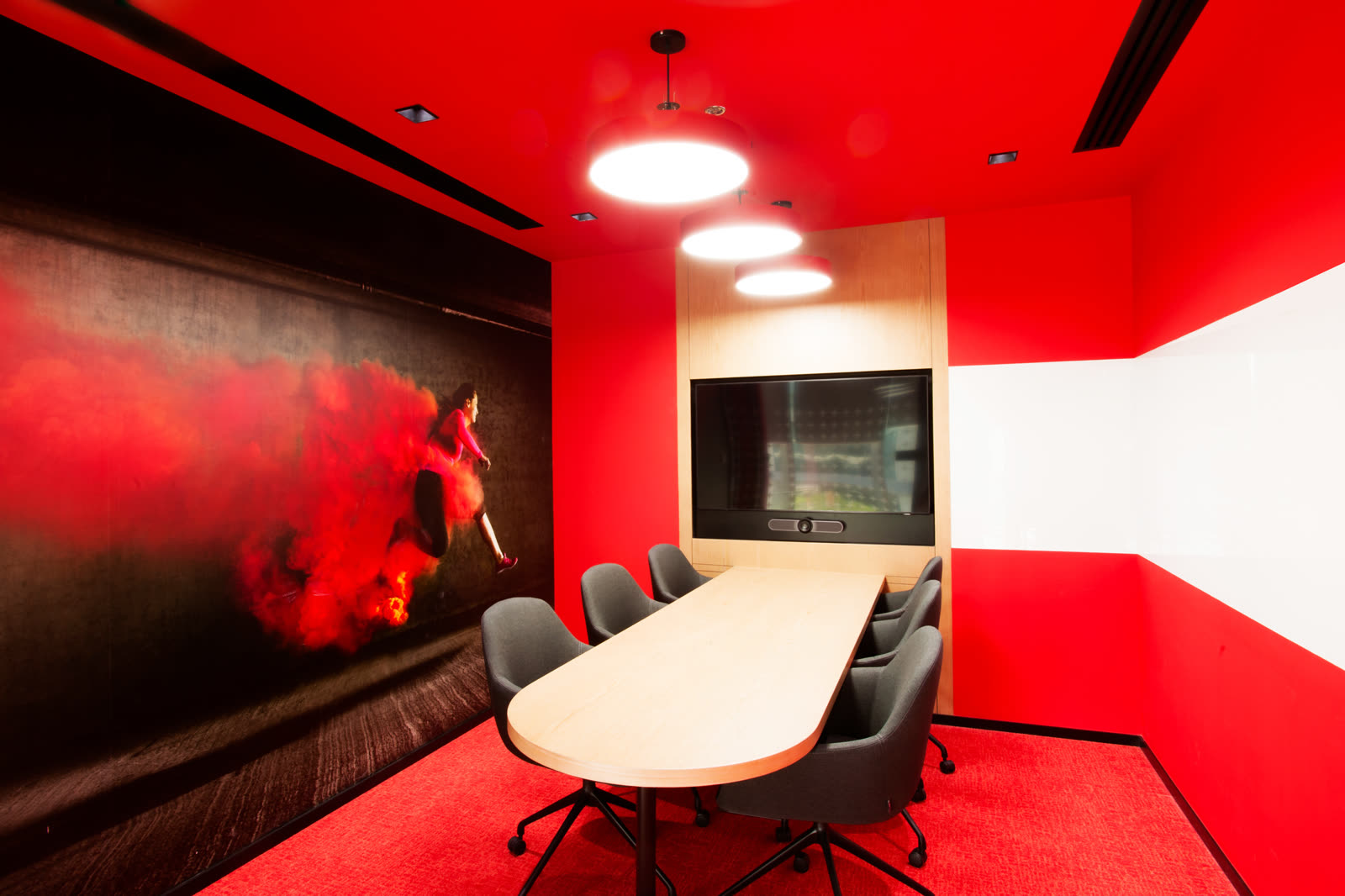 Red meeting room with a large artwork, an oval table and dark chairs