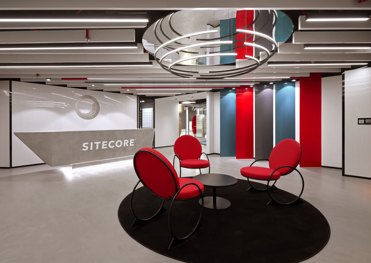 Reception with a curved Sitecore desk, red chairs and a ring light overhead
