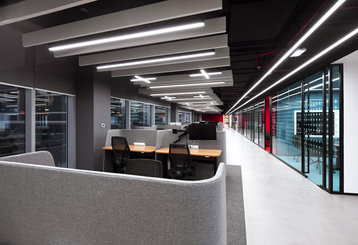 Open-plan office with linear ceiling lights, glass partitions and desks