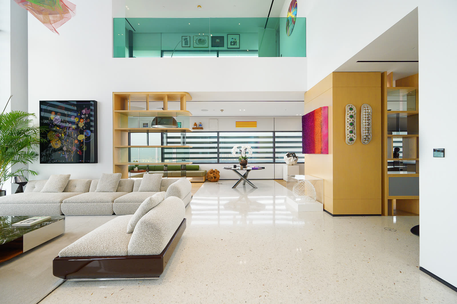 Open plan living area with a long cream sofa, colourful art and a mezzanine above