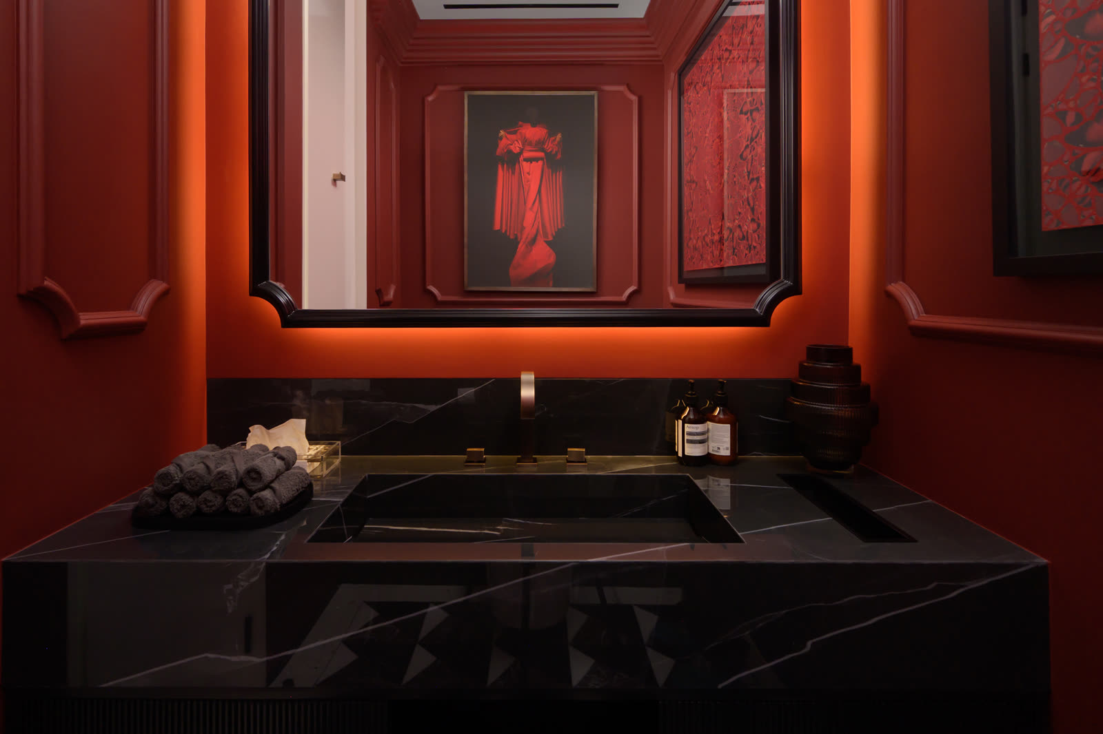 Red lacquered bathroom with a black stone vanity and a framed portrait above the basin