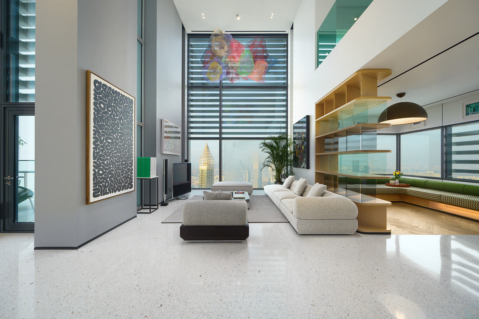 Double-height living room with a white sofa, large artwork and skyline views